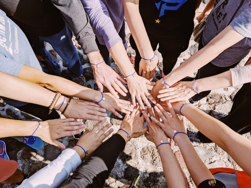 Team members join hands in a circle wearing matching bracelets
